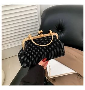 Detail of black rhinestone evening bag with gold ring handle and metal clasp in hand
