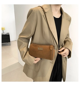 Détail d'un sac bandoulière cylindrique en daim marron avec logo en métal doré
