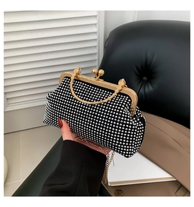 Close-up of black evening clutch with white rhinestones and gold metal frame