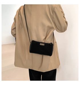 Dettaglio di una borsa a tracolla in velluto nero indossata da una modella minimal