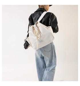 Side view of a large white nylon drawstring backpack with top handles on a model back