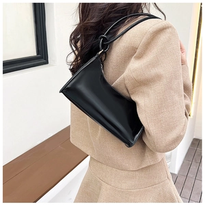 Détail de la bandoulière à nœud sur le sac sous le bras minimaliste en cuir verni noir