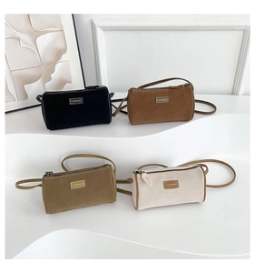 Détail de quatre sacs cylindriques en velours en noir, marron, vert et beige élégants