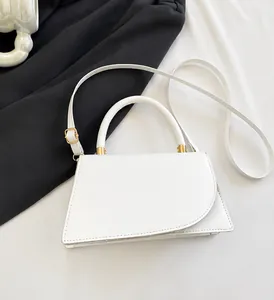 Close-up of minimalist white leather handbag with asymmetric flap and gold hardware detail