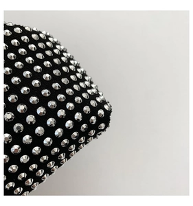 Close-up of black fabric texture with rows of shiny silver rhinestones on a stylish handbag