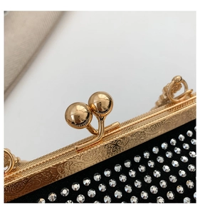 Close-up of golden embossed metal frame and double ball clasp on black rhinestone clutch