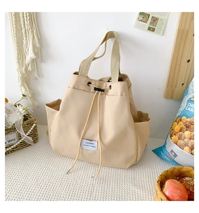 Detailed shot of beige nylon drawstring bag featuring fashion text label and side pockets