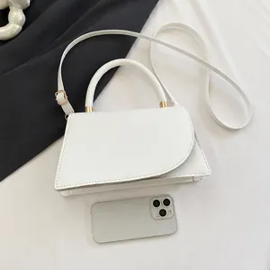 Detailed view of white crossbody bag next to a smartphone for size comparison