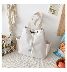 Detail of white nylon bucket bag featuring a drawstring closure and side pocket design