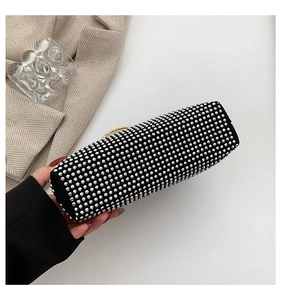 Detail of a black rhinestone handbag with silver beads and a gold metal ring handle