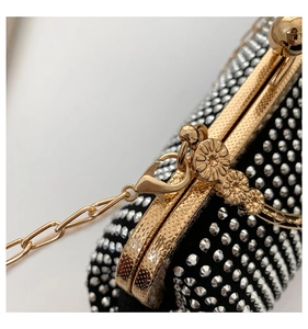 Macro detail of golden metallic lock with daisy floral motif on a studded evening clutch
