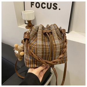 Detail of checkered bucket bag with braided leather handle and plush bear charm