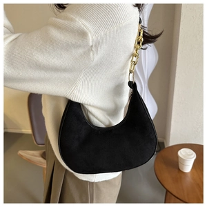 Detailed view of black suede half-moon shoulder bag with a vintage gold chain strap
