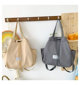 Detail of durable nylon drawstring backpacks in beige and gray with side pockets
