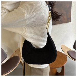 Detail of black felt hobo bag with gold chain strap worn over a white sweater