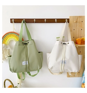 Detail of light green and beige drawstring nylon tote bags with fashion textile label