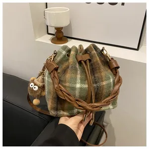 Close-up of checkered wool bucket bag with woven leather handle and plush charm detail
