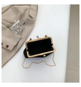 Detailed macro view of vintage black beaded handbag with gold metal frame and chain strap