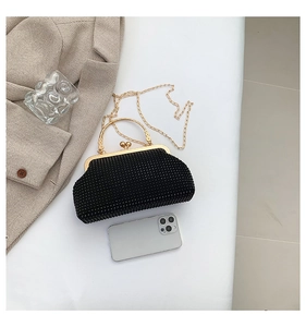 Detail of compact black beaded clutch bag with gold handle and chain strap for women