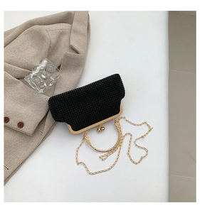 Close-up of black rhinestone evening bag with gold ring handle and metal chain strap