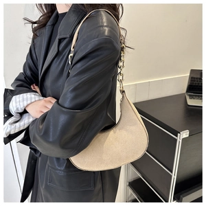 Detail of beige felt crescent shoulder bag with golden chain strap on a model