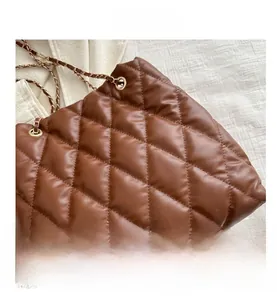 Detail van de karamelbruine gewatteerde bucketbag met glanzend kunstleer en goudketting