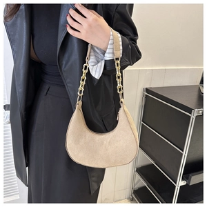 Detail of beige felt hobo bag with a thick gold chain strap and suede texture