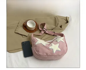 Detail of pink nylon crescent bag featuring white fleece star patches on fabric