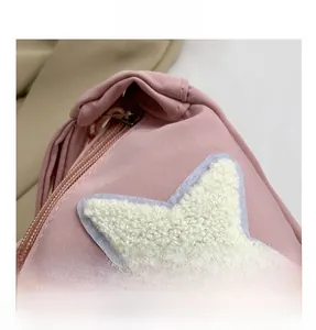 Close-up of pink nylon crossbody bag featuring a white plush star patch and zipper detail