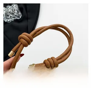 Close-up of brown lychee leather strap with stylish knot and gold metal end caps
