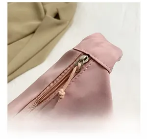 Detail of pink nylon crossbody bag featuring metallic zipper and plush star patch