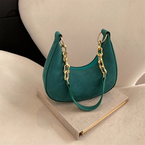 Retro dark green felt hobo bag with golden wavy chain strap on a minimalist setup