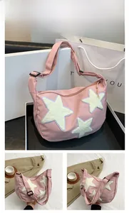 Detailed view of pink nylon crossbody bag with three white plush star patches and strap