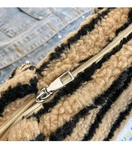 Dettaglio della cerniera in metallo argentato lucido su una borsa tote in peluche