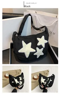 Detail view of black nylon crossbody bag featuring cute white plush star patches and wide strap