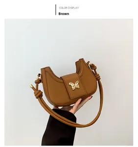 Detail of brown crescent bag featuring lychee grain leather and golden butterfly buckle