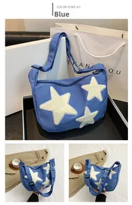 Close-up of blue nylon crossbody bag featuring plush white star patches and adjustable strap