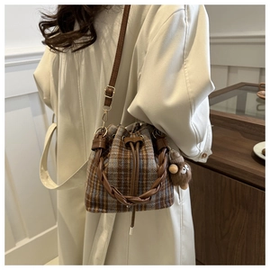 Retro plaid bucket bag with woven handle and plush monkey charm on a trench coat