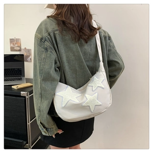 Detail view of white nylon crescent crossbody bag with plush star patches on shoulder