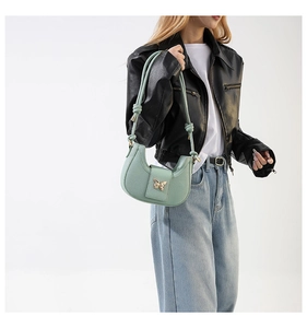 Detail of mint green hobo bag featuring gold butterfly buckle and knotted shoulder strap