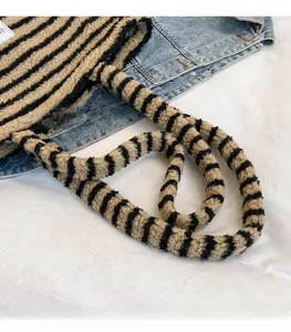 Dettaglio della tracolla in peluche sulla borsa tote a righe in pelliccia