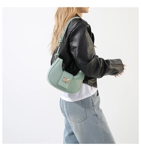 Detail of mint green crescent bag with a decorative golden butterfly metal clasp