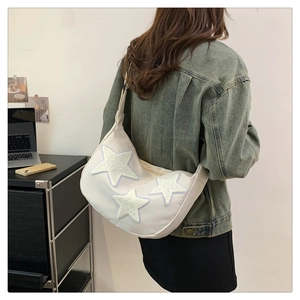 Detailed back view of a white nylon crescent bag with plush star patches and adjustable strap