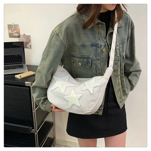 Detail of white nylon crescent bag featuring plush star patches and wide shoulder strap