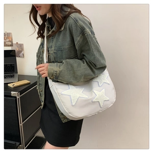 Detail shot of the white nylon crossbody bag featuring cute plush star patches and strap