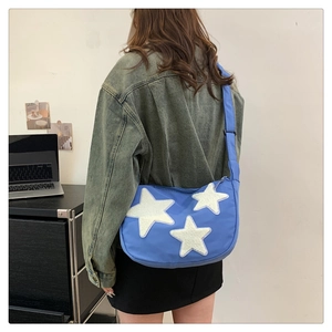 Detail view of sky blue crescent nylon crossbody bag with white plush stars on a model