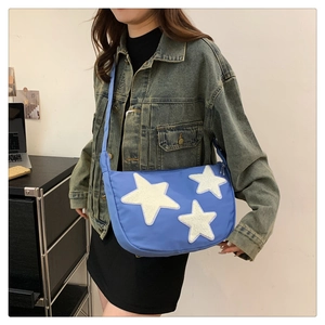 Detail view of light blue nylon crescent bag with three fuzzy white star patches