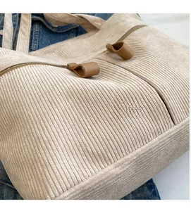 Detail of beige corduroy shoulder bag showing soft fabric texture and zipper closure