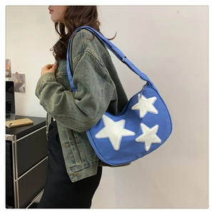 Detailed close-up of blue nylon hobo bag with white plush stars and adjustable strap