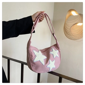 Detail of pink nylon hobo bag featuring three white plush star patches and strap
